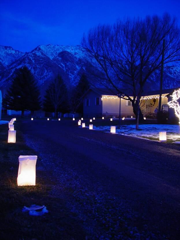 Luminaires along a snowy Alpine street at dusk with mountains behind